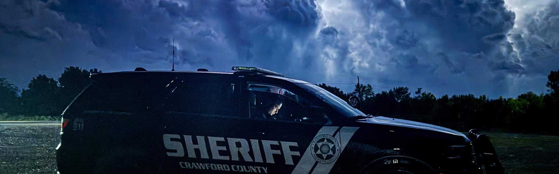 Sheriff patrol vehicle with dark clouds in the sky