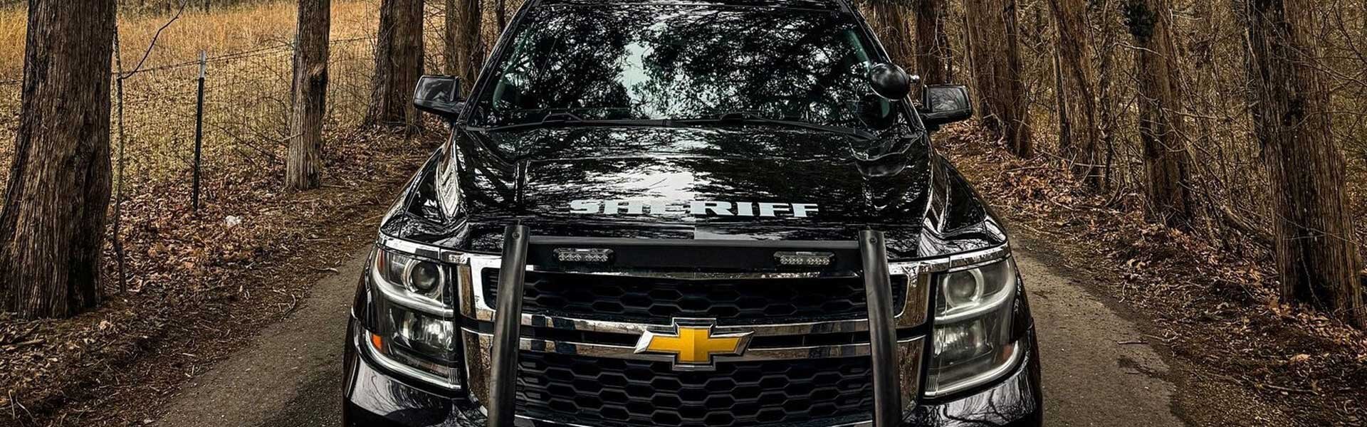 Sheriff patrol vehicle on a dirt road line with trees on both sides